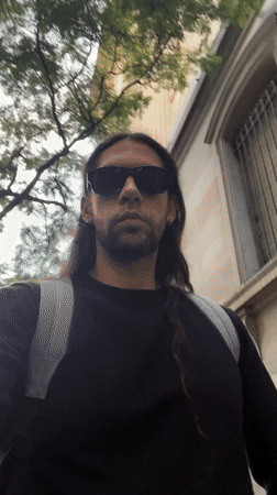 Man with backpack walks Buenos Aires sidewalk Friday evening