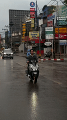 Scooter cutting through wet Chiang Mai streets on a rainy day