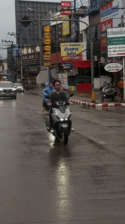 Scooter cutting through wet Chiang Mai streets on a rainy day