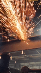 Construction worker cuts steel beams at building site