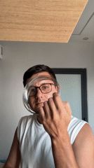 Man with glasses manipulates coiled silver object in room