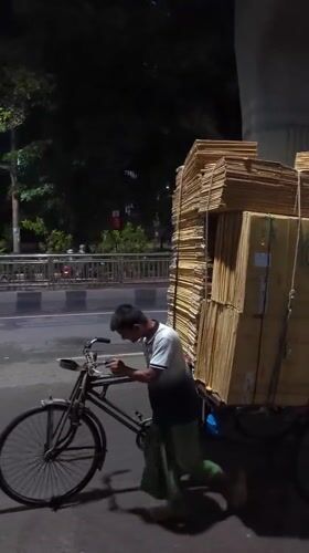 Man with bicycle cart collects cardboard in Dhaka