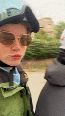 Motorcycle passenger takes selfies at traffic light behind Volkswagen