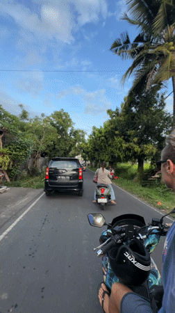 Scooter rider travels paved road in Singakerta, Indonesia
