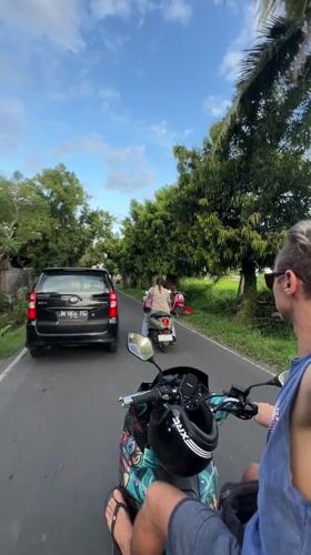 Scooter rider travels paved road in Singakerta, Indonesia