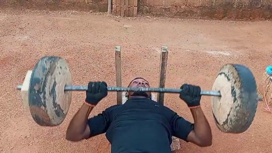 Man exercises with homemade weights in Bukuru Nigeria