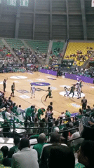 Basketball game underway featuring green and white uniformed teams