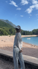 Woman photographs scenic Bečići beach on cloudy afternoon
