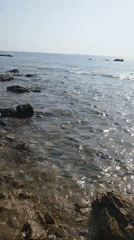 Rocky Sardinian shoreline at dawn, water and stones up close