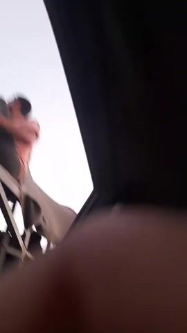 The video shows a blurry, close-up shot of a person's hand or finger, positioned in the foreground. The background is out of focus and appears to be a bright, light-colored sky or ceiling. There is a dark, angular object in the upper right portion of the frame, possibly a shadow or part of an interior structure. The lighting suggests it might be daytime.