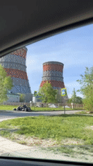 Car passes power plant cooling towers in sunny Cheboksary