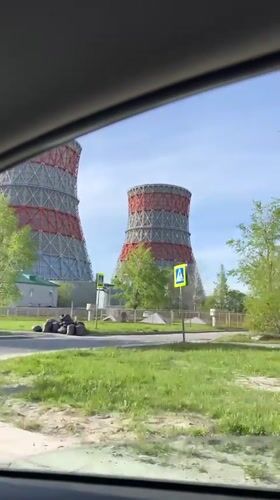 Car passes power plant cooling towers in sunny Cheboksary