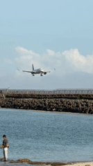 Commercial planes land over busy Kuta Beach near airport