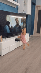 Yorkshire Terrier in pink sweater watches TV standing upright