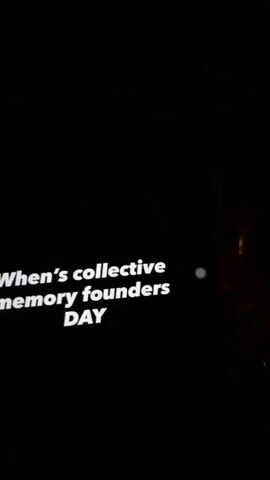 The video opens with a dark screen displaying blurry white text, which appears to read "collective founders DAY." The scene then transitions to a dimly lit bar or lounge setting. A young woman with long, reddish-brown hair, wearing a dark top, is seated at a table. She smiles directly at the camera.

In front of her is a tall glass containing a light yellow beverage with ice and a straw, possibly a cocktail. To her left, there's another glass with a darker drink and a small, white, illuminated device displaying colorful lights. The background features a vibrant mural on a red wall, depicting a stylized face, possibly a calavera, adorned with flowers and tropical plants like pineapples. The overall ambiance is cozy and atmospheric, suggesting an evening outing. The woman appears relaxed and happy, posing for the camera while enjoying her drink.