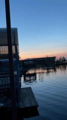 Man observed at Chaikovsky waterfront during sunset, motorcycle nearby