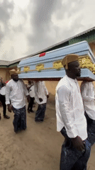 Funeral procession with pallbearers carrying coffin in Nigerian village