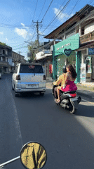 Scooter passengers follow silver minivan in Ubud streets