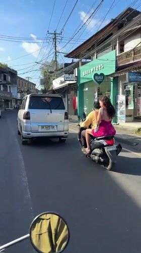 Scooter passengers follow silver minivan in Ubud streets