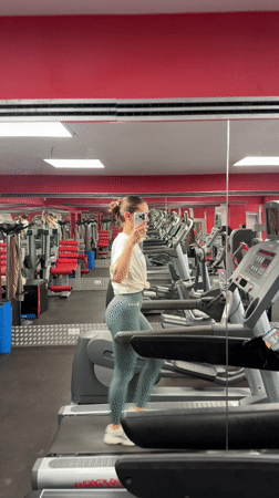 Woman uses phone while exercising on treadmill in Sofia gym