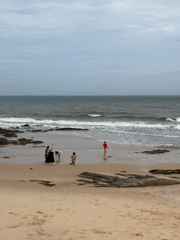Overcast morning on a rocky Mũi Né beach with families at the shore