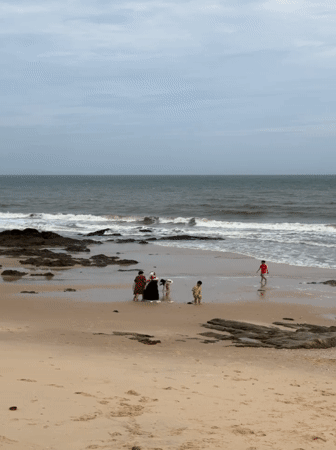 Overcast morning on a rocky Mũi Né beach with families at the shore