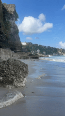 Rocky shoreline and calm surf on a clear Bali afternoon