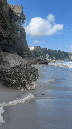 Rocky shoreline and calm surf on a clear Bali afternoon