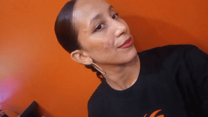 Woman in black shirt observed against orange wall in Pampatar