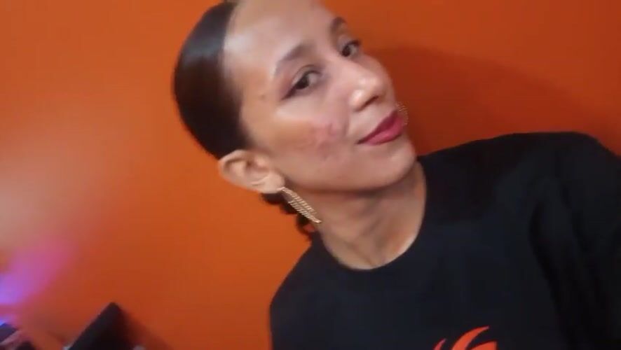 Woman in black shirt observed against orange wall in Pampatar