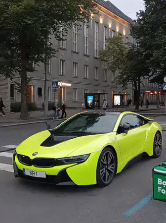 Neon BMW i8 parked outside Tallinn's green-domed landmark