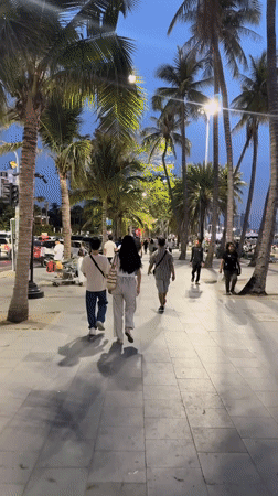 Sunset strollers enjoy Pattaya beachfront promenade and beach scene
