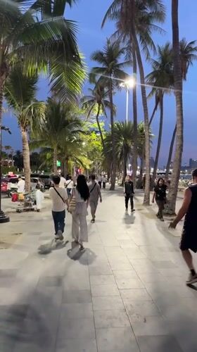 Sunset strollers enjoy Pattaya beachfront promenade and beach scene