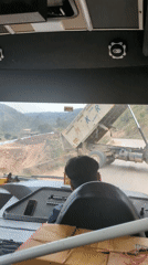 Dump truck deposits gravel on dirt road in Basa Balhu