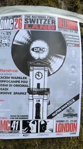 The video shows a poster attached to a tree. The poster is for a DJ championship called DMC 26 The National Final SwitzerLand Delémont, taking place on September 26th, 2026. It features a large image of a vinyl record and a clock tower. Below the main image, there is a list of "Aftershow" performers: Kacem Wapalek, Hippocampe Fou, Yoshi Di Original, Deadi, and Groove Sparkz. The poster also lists judges: Mr. Myst, D-Sparkz, and two unreadable names. The host is Remo. At the bottom, it mentions DMC 41 The World DJ Championships and the website www.dmcdjchamps.com. There is also information about a halftime show and the DMC World Championships in London from November 12th-15th, 2026. The poster is white with red and black text and graphics. The tree bark is visible in the background, covered in moss. A white ribbon is wrapped around the tree, holding the poster in place. The video is a close-up shot of the poster, with slight movement as if being panned or held by hand.