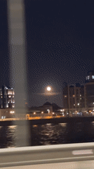 Full moon rises over illuminated Saint Petersburg waterfront