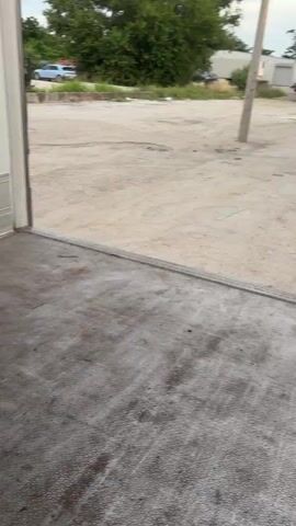 The video opens with a view of the floor and lower wall of a truck trailer. The camera then pans up to reveal a green electric pallet jack in the center of the trailer. The trailer is filled with stacks of cardboard boxes on pallets, arranged in two columns. The boxes are red and white with a logo visible. The camera continues to pan, showing more of the stacked boxes, and then the video ends.