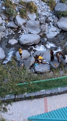Monks and visitors gather at rocky riverbed in Bhagsu