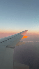 Passenger documents sunset flight with wing view and entertainment setup