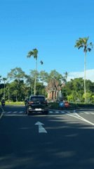 Black car stops at tropical roundabout crosswalk