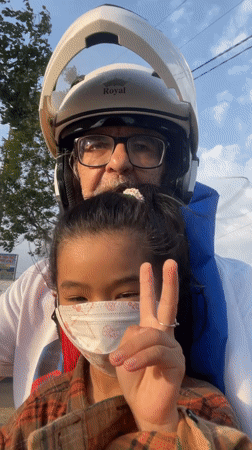 Man and girl ride motorcycle in Vietnam, girl flashes peace sign