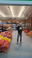 Man juggles cabbages in Bulgarian grocery store produce aisle