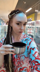 Woman drinks from metal cup in Izhevsk commercial space