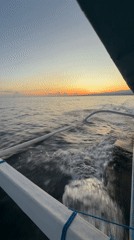 Boat crosses Bali waters at sunset near industrial coastline