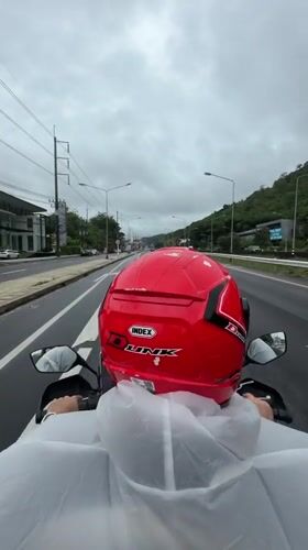 Motorcyclist rides wet roads in Ko Kaeo wearing protective gear