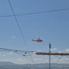 Red helicopter hovering above a tangle of dark cables
