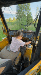 Kid behind the wheel of an old yellow tractor in rural Russia