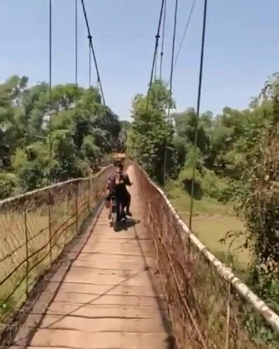 Motorcycle riders cross wooden suspension bridge in Battambang