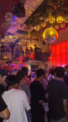 Live band performs at disco ball-decorated crowded bar venue