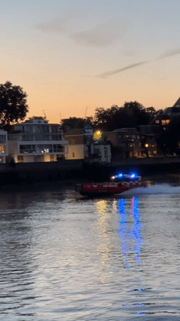 Fire rescue boat speeds along the Thames at dusk